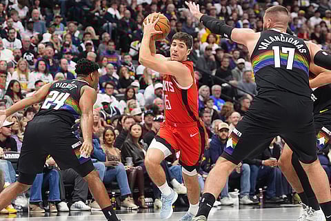 Houston Rockets guard Reed Sheppard, center, drives to the basket between Denver Nuggets guard Jalen Pickett, left, and center Jonas Valančiūnas (17) in the second half of an NBA basketball game in Denver. 