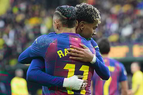 Barcelona's Raphinha, back, celebrates with his teammate Barcelona's Lamine Yamal after scoring the opening goal from a penalty kick during the Spanish La Liga soccer match between Villarreal and Barcelona in Villarreal, Spain.