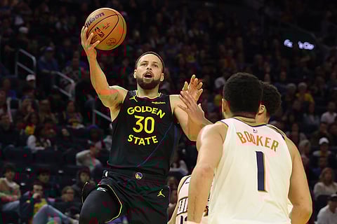 Golden State Warriors guard Stephen Curry (30) shoots against Phoenix Suns guard Devin Booker (1) during the second half of an NBA basketball game in San Francisco.