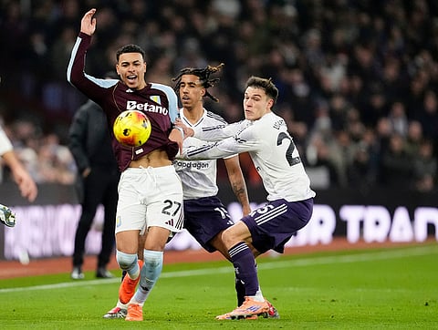 Aston Villa's Morgan Rogers, left, battles for the ball with Manchester United's Leny Yoro, centre, and Manuel Ugarte, right, during the Premier League soccer match between Aston Villa and Manchester United, in Birmingham, England.