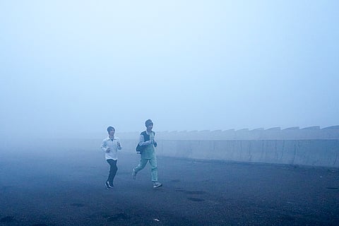 People jog amid dense fog on a winter morning, at Mayur Vihar area, in New Delhi. 