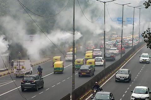 Water sprinklers operate under dense fog on a winter morning, in New Delhi.