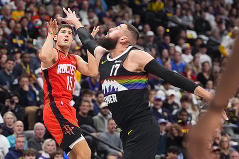 Houston Rockets guard Reed Sheppard, left, shoots a 3-point basket over Denver Nuggets center Jonas Valančiūnas (17) in the second half of an NBA basketball game in Denver. 