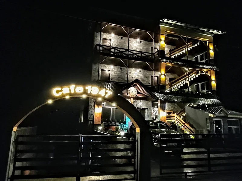 Exterior of Cafe 1947 in Manali at night with an illuminated sign