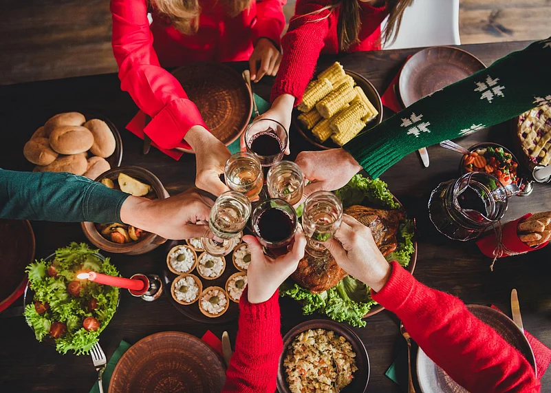 People toast drinks over a festive holiday dinner table