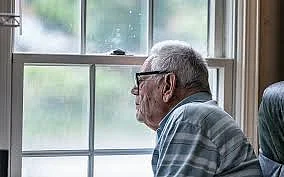 An elderly man looking out the window