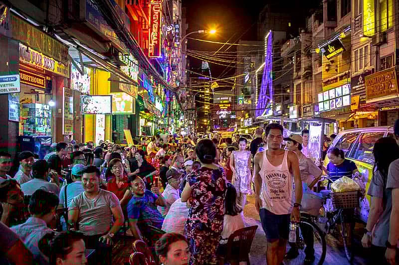 Crowded night scene on Bui Vien street in Ho Chi Minh City with bright neon lights and people