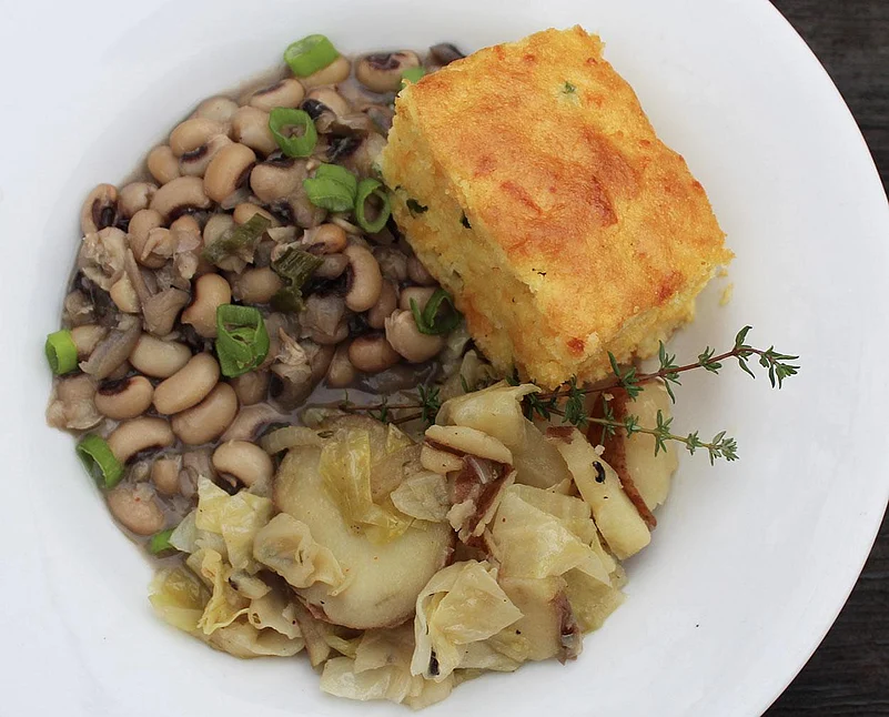A plate of black-eyed peas, cornbread, and cabbage