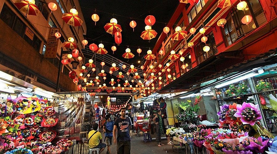 Busy night market at Petaling Street in Kuala Lumpur with crowds and hanging red lanterns