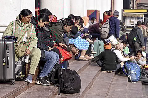 Passengers wait outside the New Delhi railway station amid delay in train services caused by winter fog, in New Delhi.