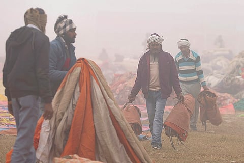 Workers dismantle an event setup during a cold and foggy winter morning, in Prayagraj.