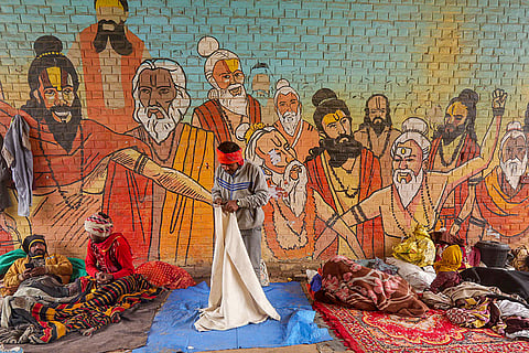 People take shelter under a foot overbridge on a cold winter morning, in Prayagraj.