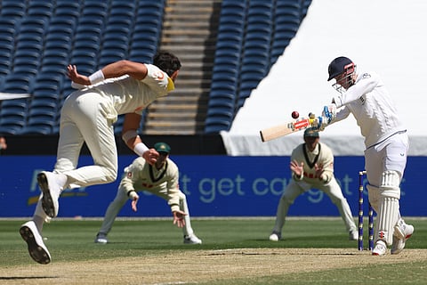England's Harry Brook, right, swings wildly at a delivery from Australia's Mitchell Starc, left, during their Ashes cricket test match in Melbourne.