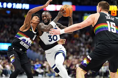 Minnesota Timberwolves center Julius Randle drives between Denver Nuggets guard Peyton Watson, left, and center Nikola Jokić in the second half of an NBA basketball game in Denver. 