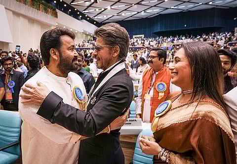 Malayalam film actor Mohanlal being greeted by Bollywood actor Shah Rukh Khan as fellow actor Rani Mukerji looks on during the 71st National Film Awards, in New Delhi, Tuesday, Sept. 23, 2025.