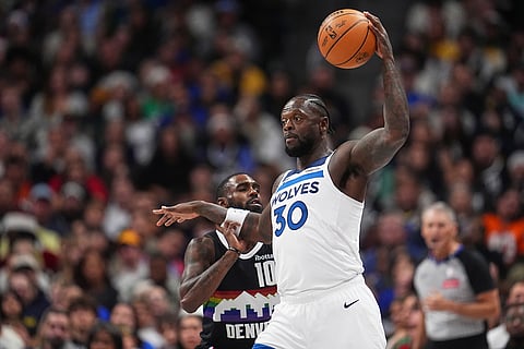 Minnesota Timberwolves center Julius Randle, front, collects a pass as Denver Nuggets guard Tim Hardaway Jr. defends in the first half of an NBA basketball game, in Denver. 
