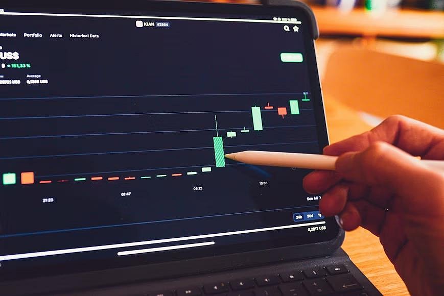 Hand using a stylus to analyze a stock market chart on a tablet