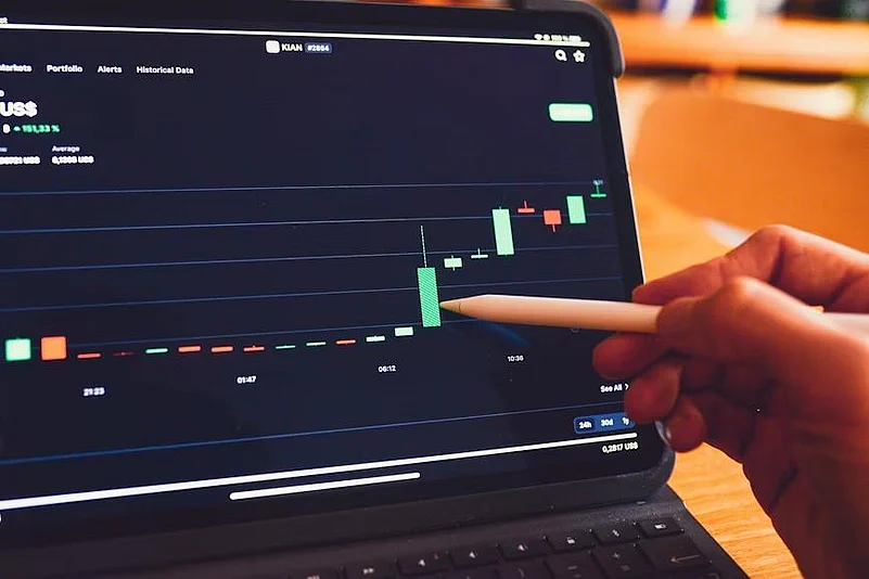 Hand using a stylus to analyze a stock market chart on a tablet