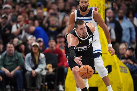 Denver Nuggets center Nikola Jokić, front, flips a loose ball as Minnesota Timberwolves center Rudy Gobert defends in overtime of an NBA basketball game in Denver. 