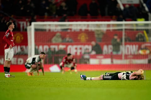 Newcastle's Lewis Hall, right, lays on the pitch after his teams loss during the English Premier League soccer match between Manchester United and Newcastle in Manchester, England.