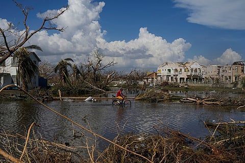 A man rides his bicycle through an inundated street during the aftermath of Hurricane Melissa, Oct. 30, 2025, in Black River, Jamaica.