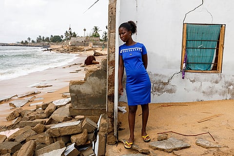 Afeli Bernice Adzo leans against the remains of her father's room as she looks at the ocean that destroyed her family home March 5, 2025, in Avegadzi, Ghana.