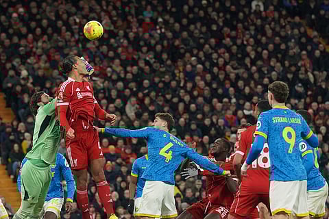 Liverpool's goalkeeper Alisson, left, makes a save in front of Wolverhampton Wanderers' Santiago Bueno, center, during the English Premier League soccer match between Liverpool and Wolverhampton Wanderers in Liverpool.