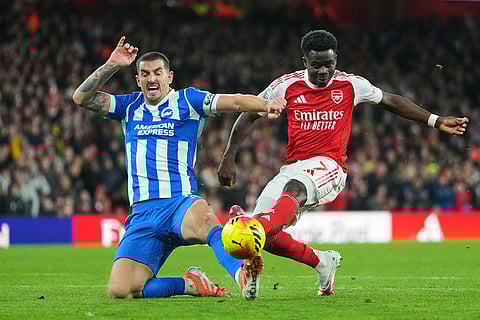 Arsenal's Bukayo Saka and Brighton's Lewis Dunk challenge for the ball during the English Premier League soccer match between Arsenal and Brighton and Hove Albion in London.