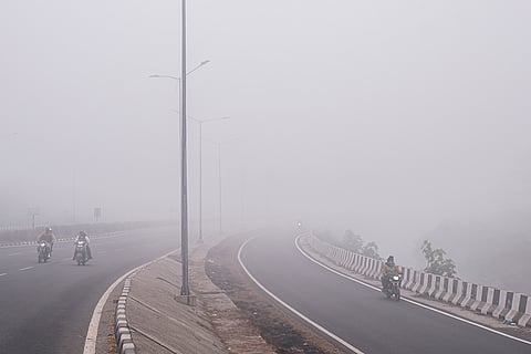 Motorcyclists proceed along a highway as dense fog reduces visibility across Punjab, in Amritsar.