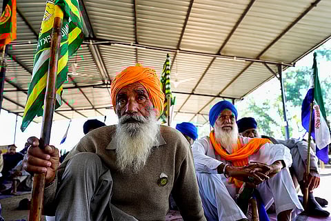 An elderly farmer sits at the daily assembly at Shambhu border, listening to the leaders speak from the stage on January 13, 2025
