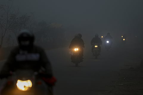 Vehicles ply on a road amid low visibility on a foggy winter morning, in Jammu.