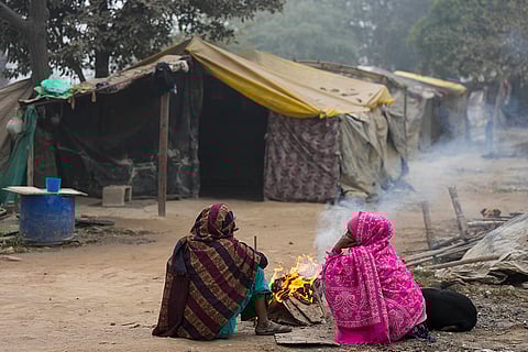 People sit around a bonfire on a foggy winter day, in New Delhi.