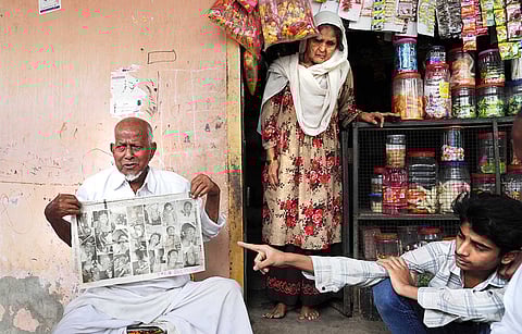 84-year-old Shaikh Abrahim Supru clutches an old newspaper clipping. His hands tremble, the paper thins with age, but the face in the photo is clear, that of Shaikh Rafique Shaikh Mustafa, his son-in-law.