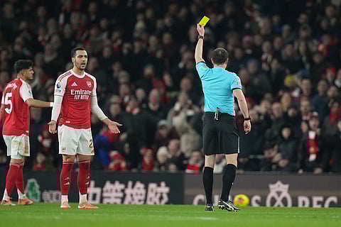 Arsenal's Mikel Merino, second left, receives a yellow card by a referee during the English Premier League soccer match between Arsenal and Aston Villa in London.