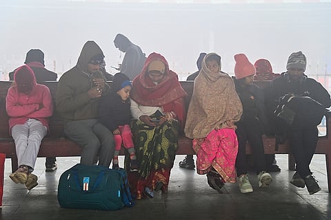 Passengers wait on a platform amid train delays and cancellations due to fog, in Prayagraj.