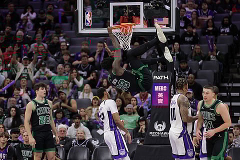 Boston Celtics center Neemias Queta (88) hangs on the rim after dunking the ball during the second half of an NBA basketball game against the Sacramento Kings, in Sacramento, California.