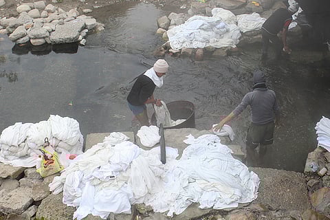 Washermen wash clothes in a pond, on a cold winter morning, in Rishikesh.