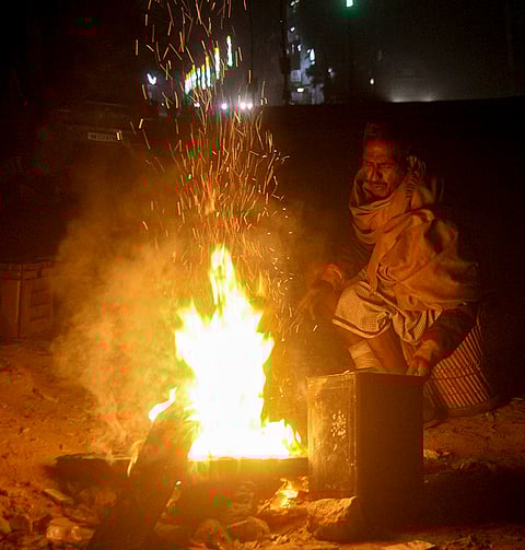 A man warms himself near a makeshift fire on a cold winter morning, in Gurugram, Haryana.