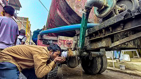 A man drinks water from a tanker amid a contaminated water crisis at Bhagirathpura, in Indore.