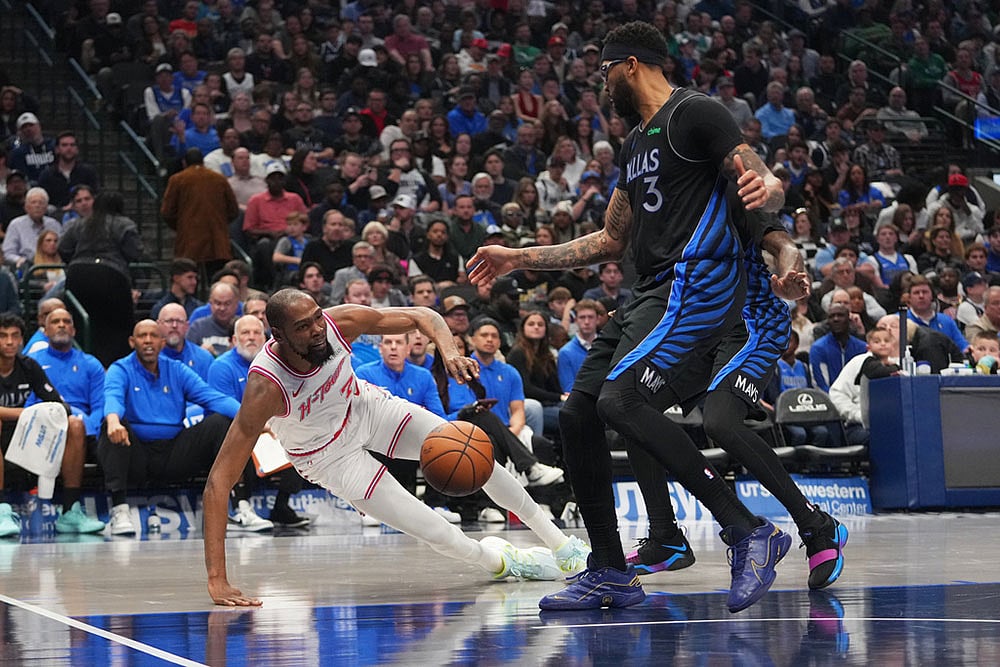 Houston Rockets forward Kevin Durant, left, falls to the floor while attacking against Dallas Mavericks forward Anthony Davis (3) and a teammate during the first half of an NBA basketball game in Dallas. - | Photo: AP/Julio Cortez