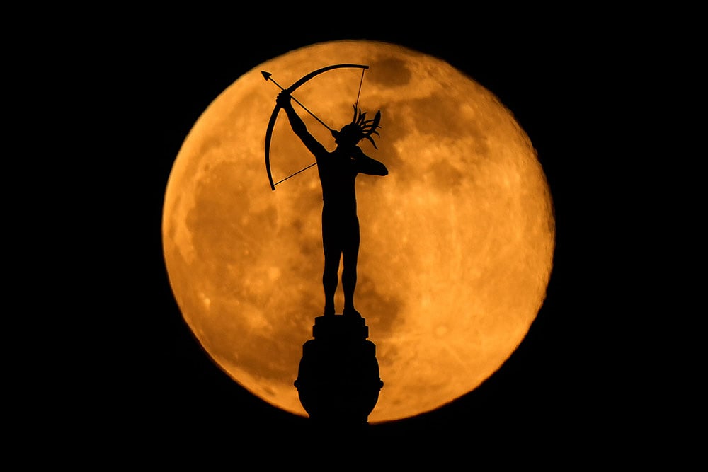 | Photo: AP/Charlie Riedel : The full moon rises behind the statue, "Ad Astra," atop the Kansas Statehouse in Topeka, Kan.