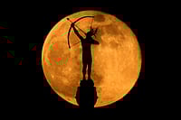 | Photo: AP/Charlie Riedel : The full moon rises behind the statue, "Ad Astra," atop the Kansas Statehouse in Topeka, Kan.