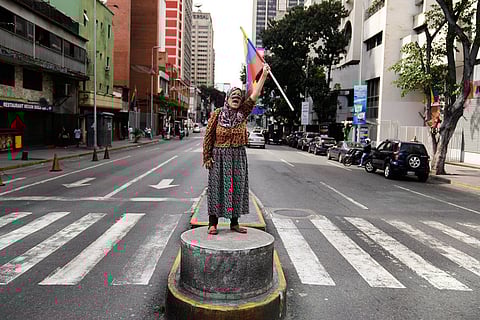 A supporter of Venezuelan President Nicolas Maduro stands on a median strip waving a national flag in Caracas, Venezuela, after U.S. President Donald Trump announced that Maduro had been captured and flown out of the country.