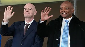 | Photo: AP/Themba Hadebe : CAF President Patrice Motsepe and FIFA President Gianni Infantino wave from the tribune during the Africa Cup of Nations round of 16 soccer match between South Africa and Cameroon in Rabat, Morocco, Sunday, Jan. 4, 2026.