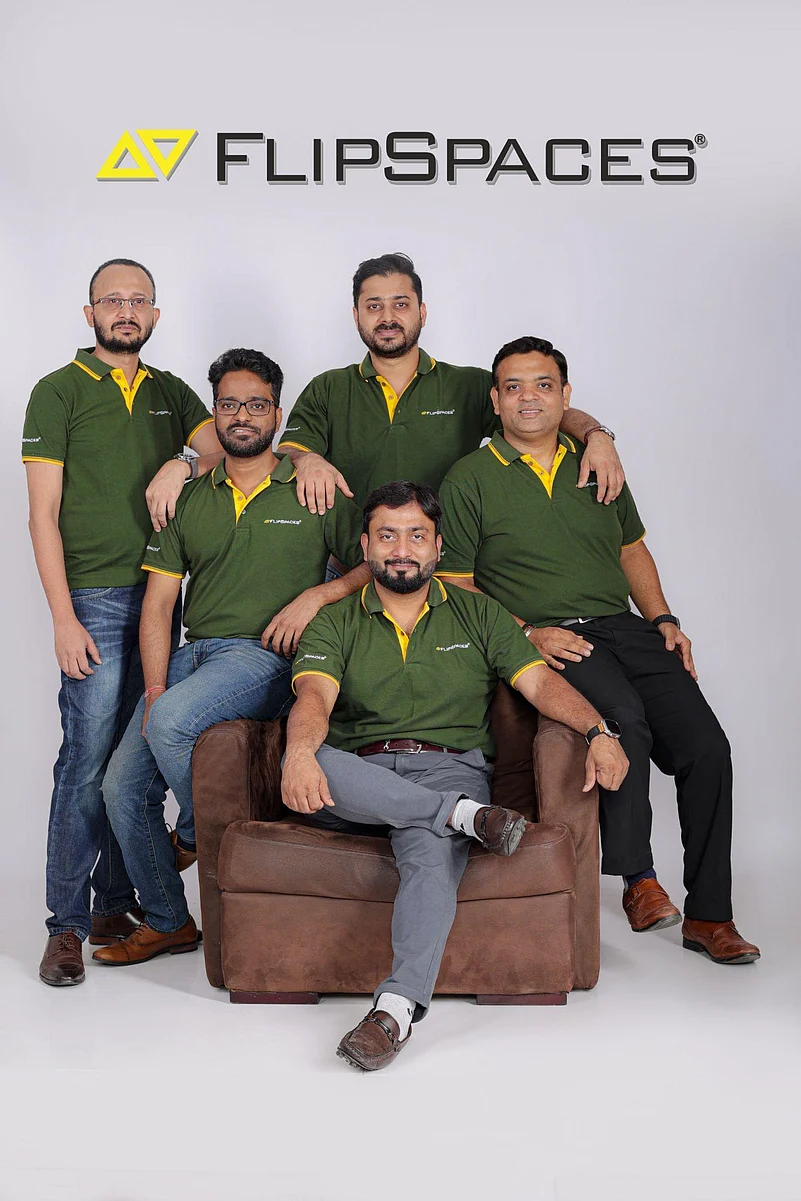 Five men in matching green polo shirts posing for a group photo under a Flipspaces logo.