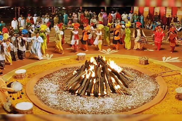 People in traditional attire performing around a large bonfire during a Lohri celebration.