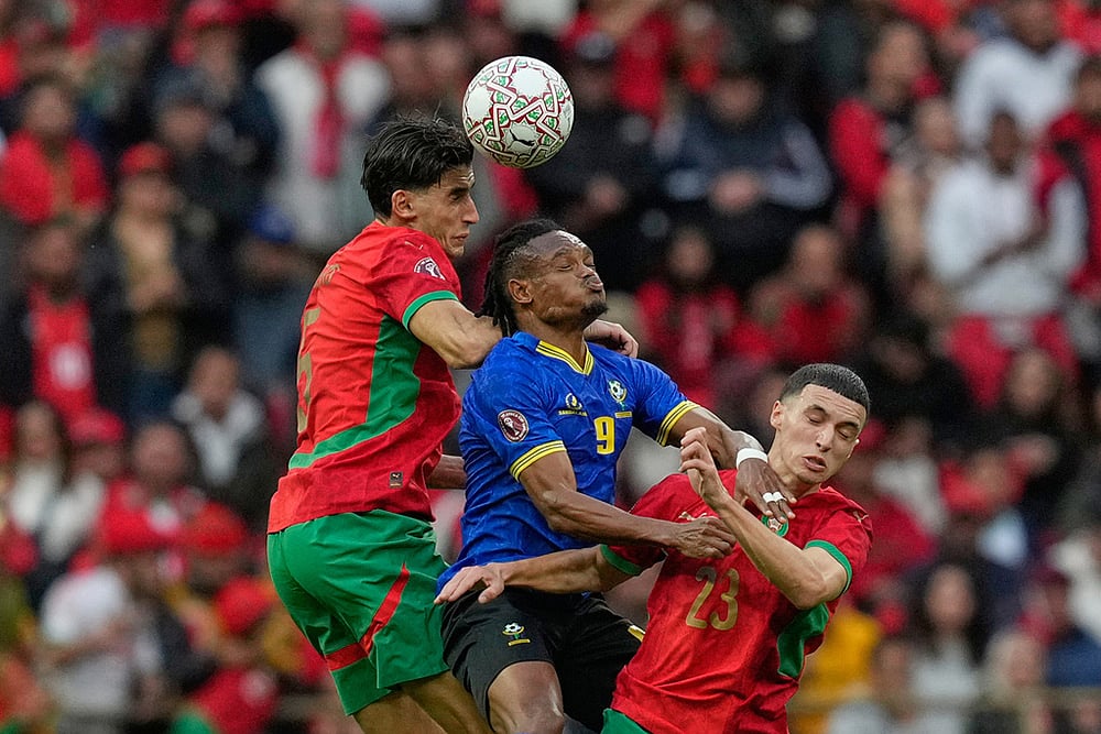 Tanzania's Selamani Mwalimu, center, fights for the ball with Morocco's Nayef Aguerd, left and Bilal El Khannouss during the Africa Cup of Nations round of 16 soccer match between Morocco and Tanzania in Rabat, Morocco. - | Photo: AP/Mosa'ab Elshamy