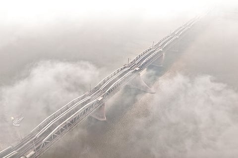 A dense layer of fog shrouds the Old Yamuna Bridge on a winter morning, in Prayagraj.