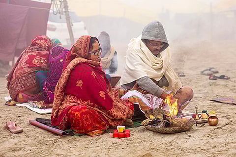 Devotees perform rituals amid fog and low visibility during the Magh Mela, at Sangam in Prayagraj.