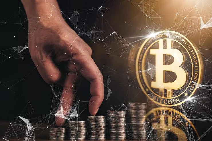 Fingers climb coins towards a glowing Bitcoin symbol